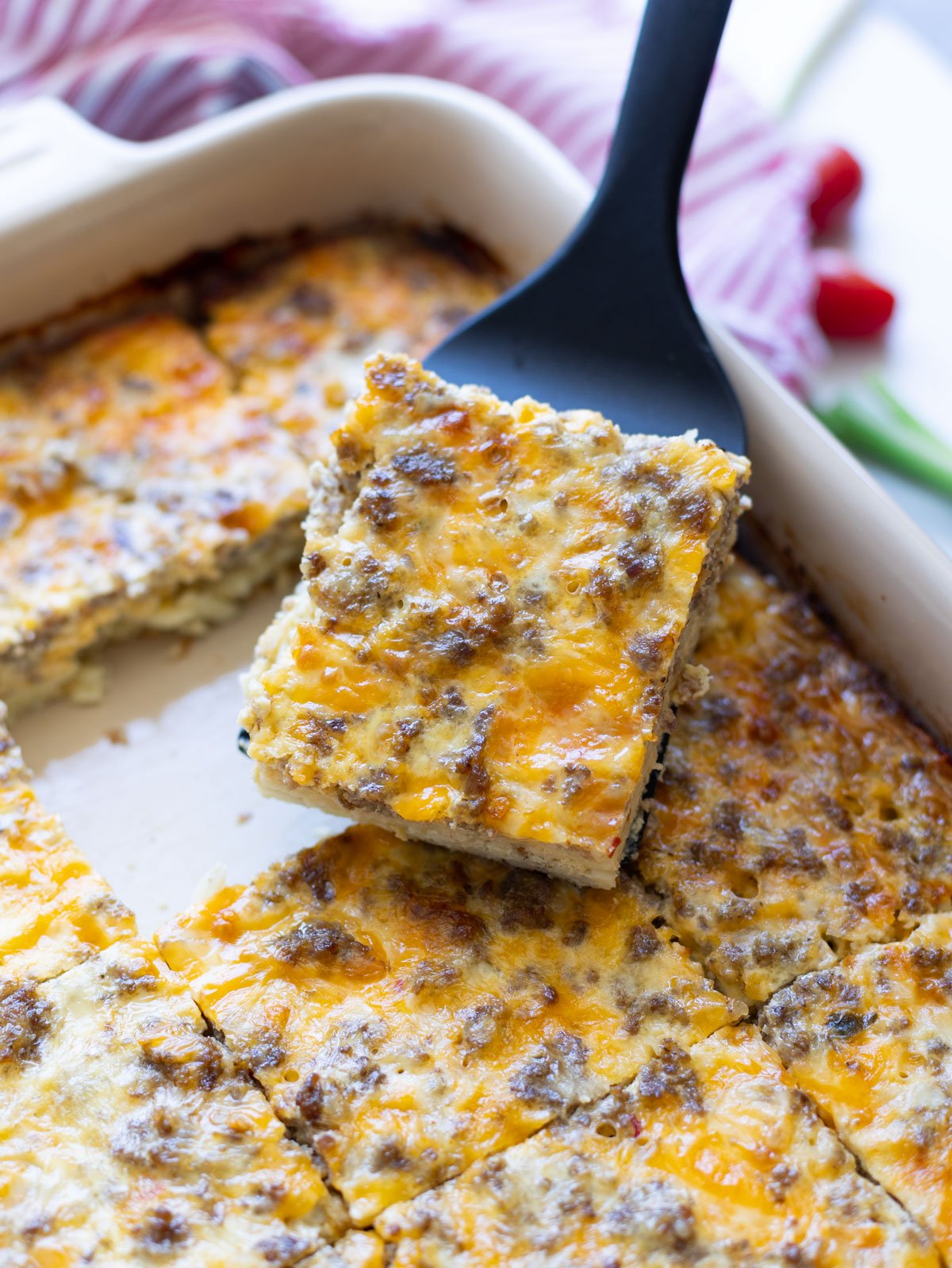 Serving a slice of breakfast casserole with hash browns and sausage. 