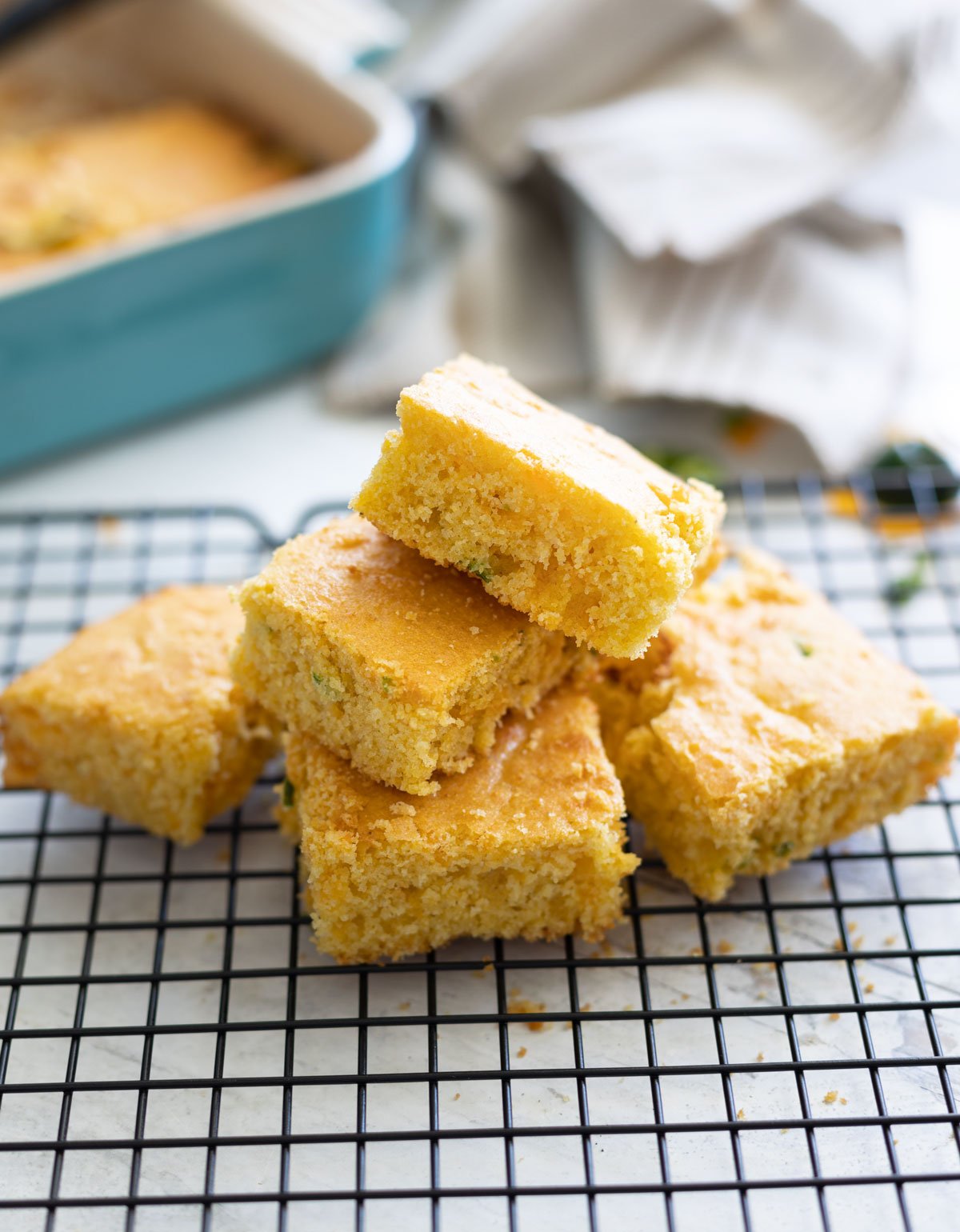 Stack of cheddar jalapeno cornbread  squares on a cooling rack. 