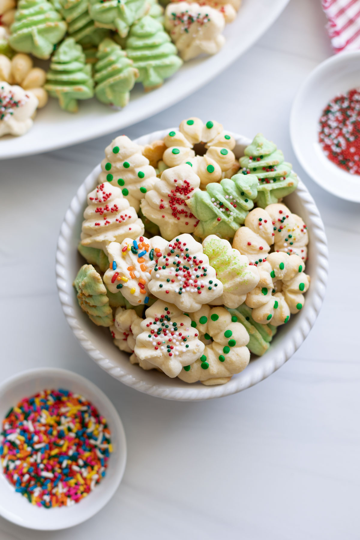 A bowl of almond spritz cookies with sprinkles for toppings.