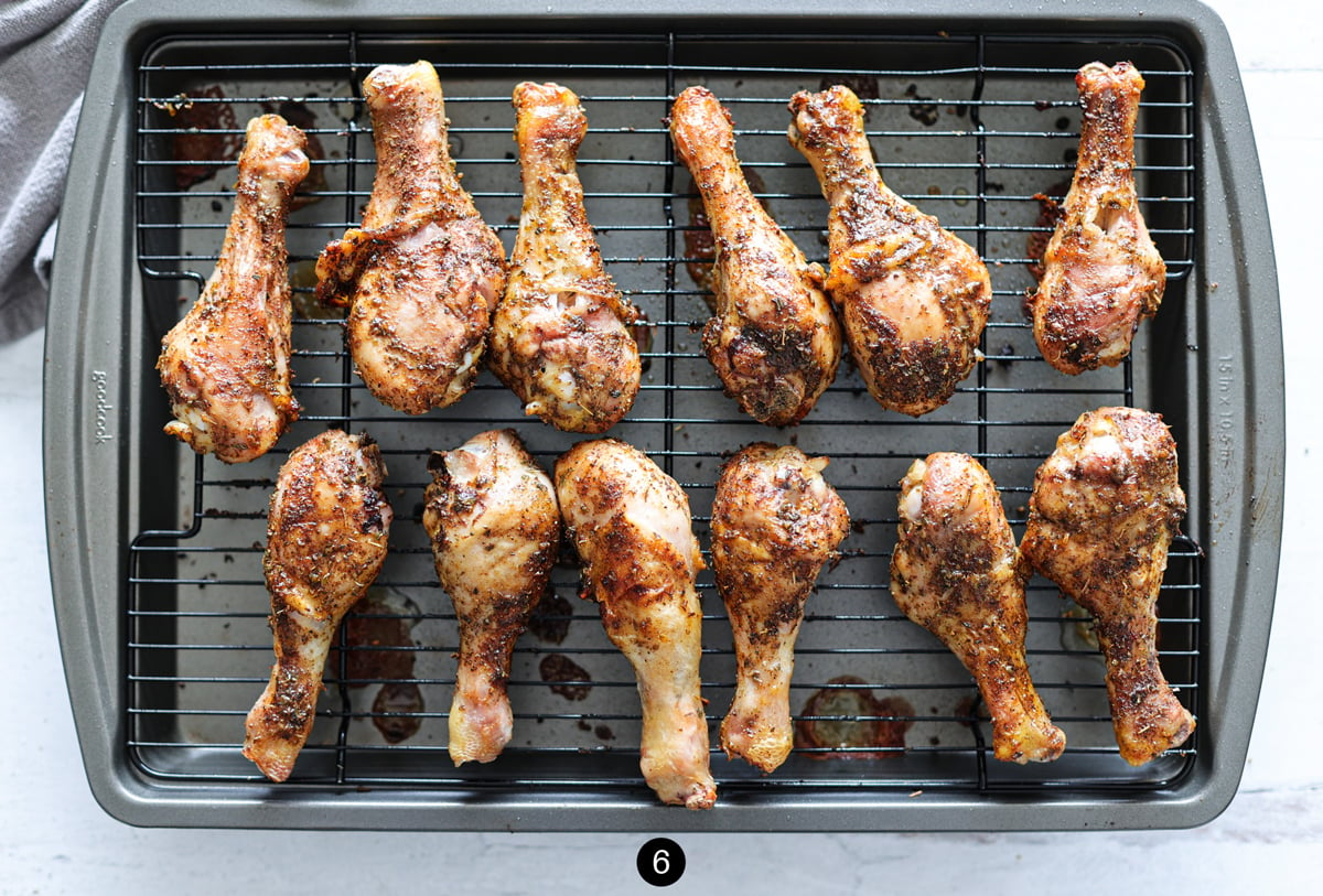 Baked chicken legs on a wire rack over a baking pan.