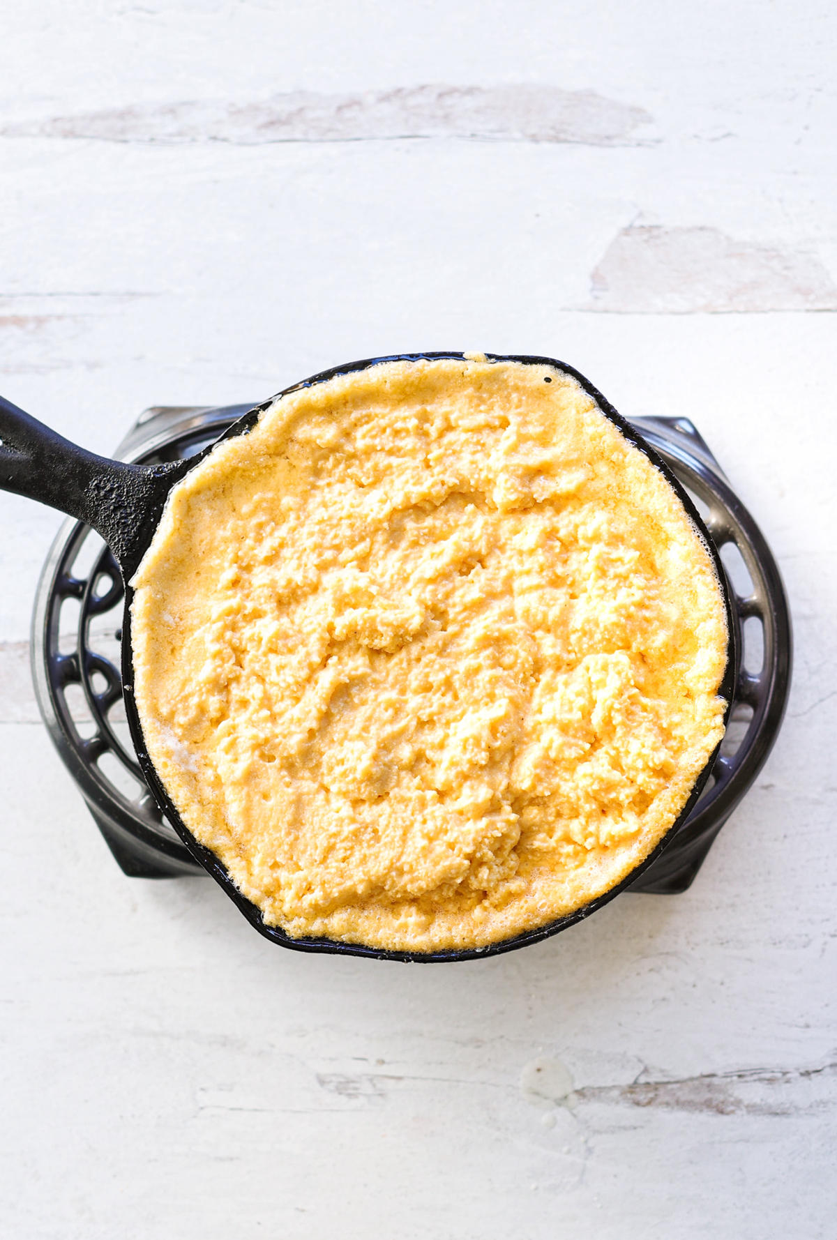 Cornmeal batter in a cast iron skillet getting ready to be baked. 