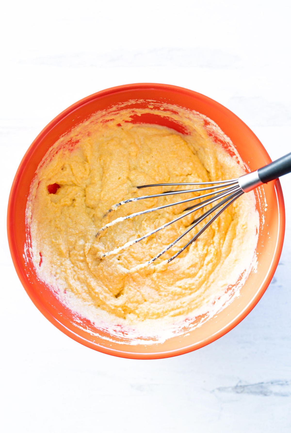 Person whisking together cornmeal batter in a bowl.