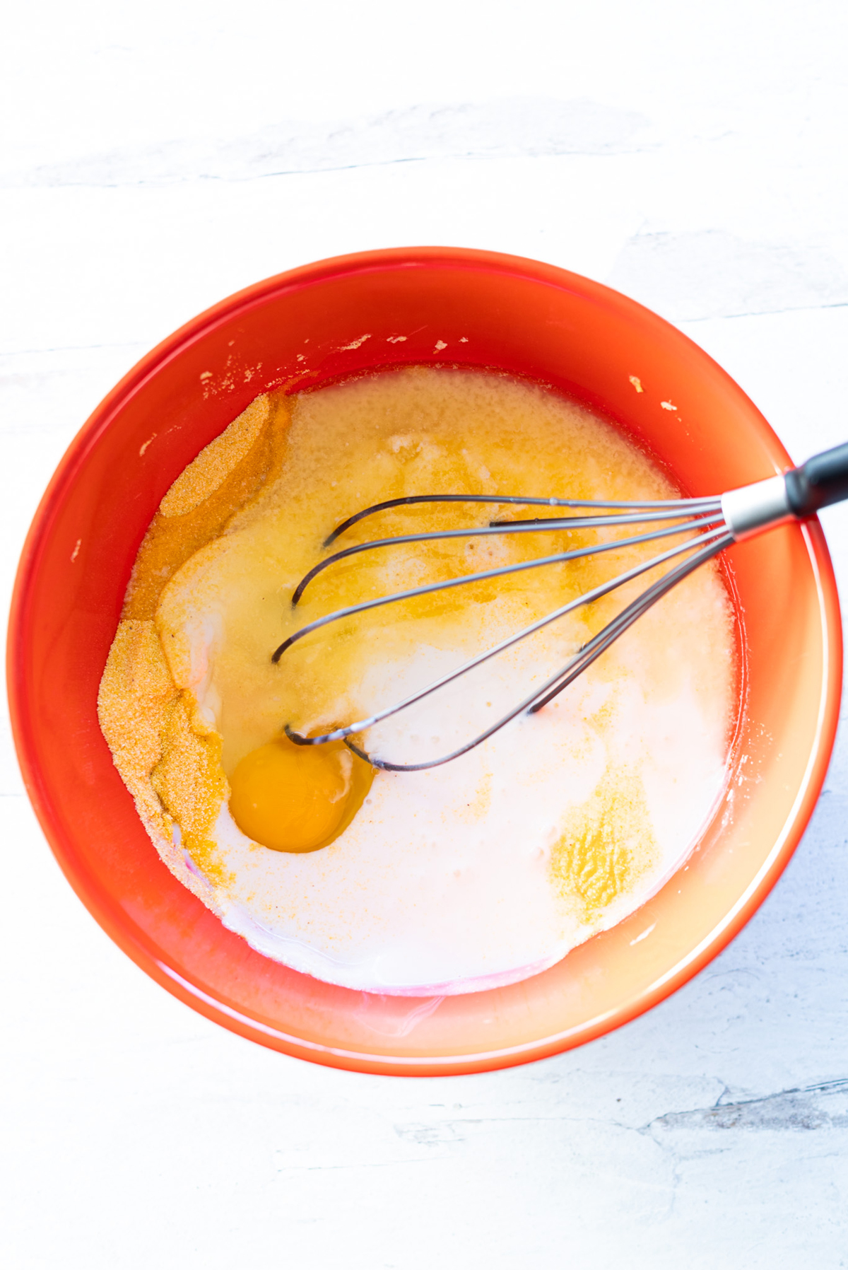Person whisking wet ingredients into a bowl of dry ingredients to make cornbread.