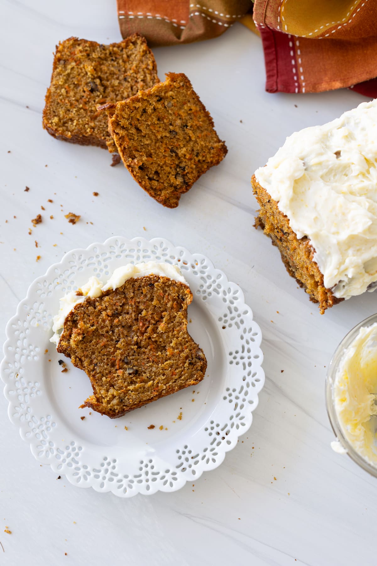 Sliced piece of carrot bread on a plate topped with lemon cream cheese frosting. 