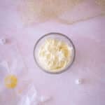 Icing in a glass container on a pink counter.