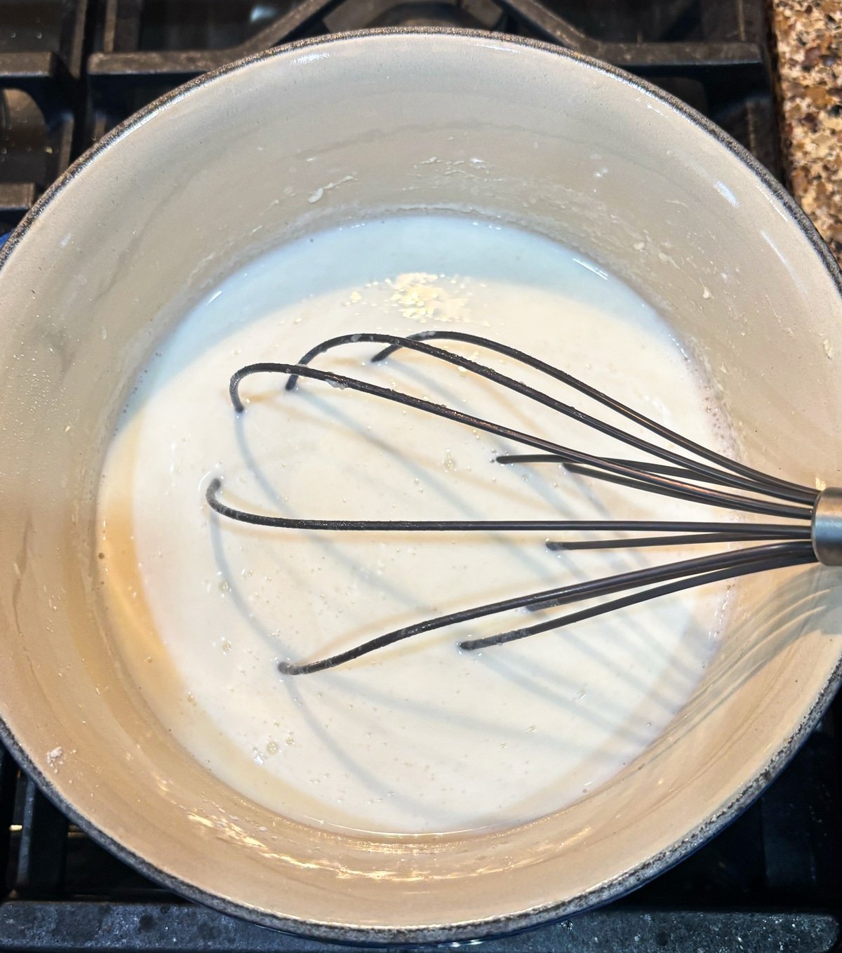 Person whisking sauce in a saucepan.